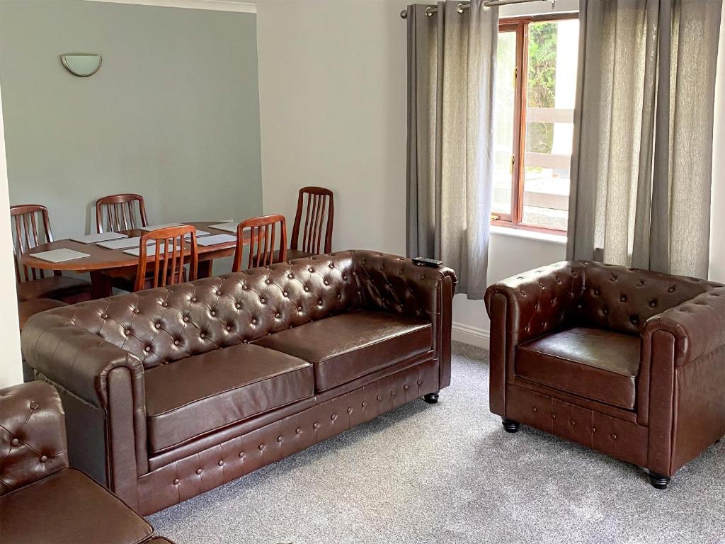 a leather couch and chair in a living room at Rosecraddoc Manor - Riverbank in Saint Cleer