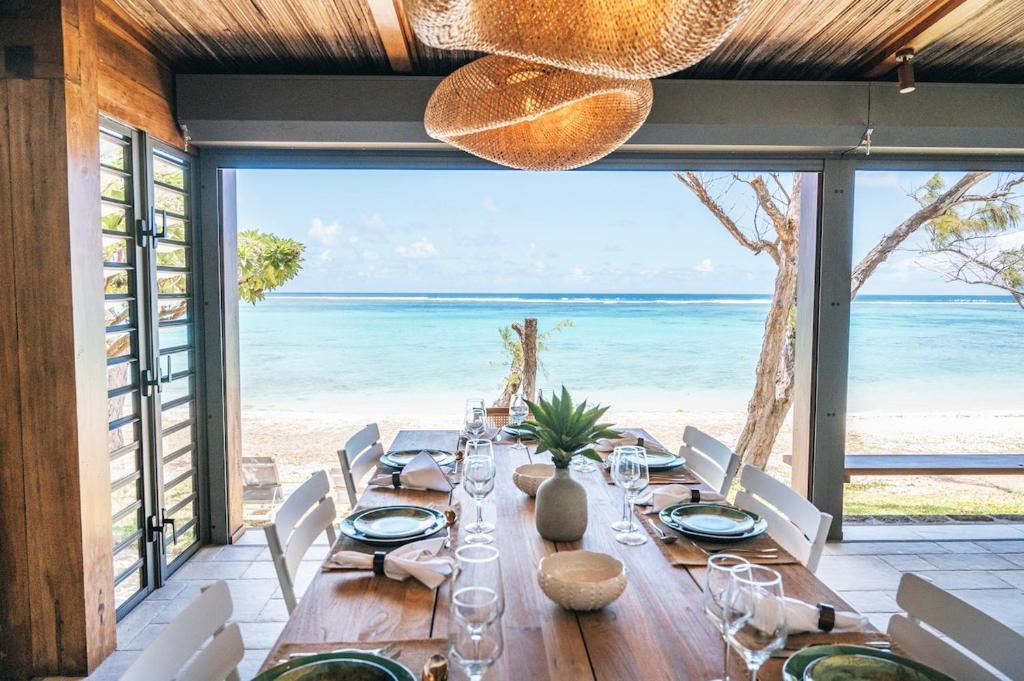 a long table with white chairs and a view of the ocean at La Pépite Villa in Pointe d'Esny