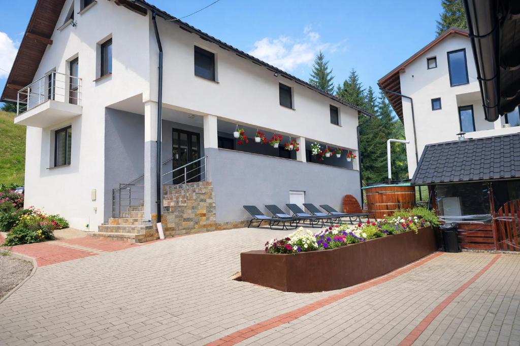 a white building with chairs and flowers in a courtyard at Casa de vacanta Naty in Colibiţa
