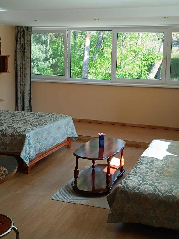 a room with two beds and a table and a window at Apartamentai Nidoje in Nida