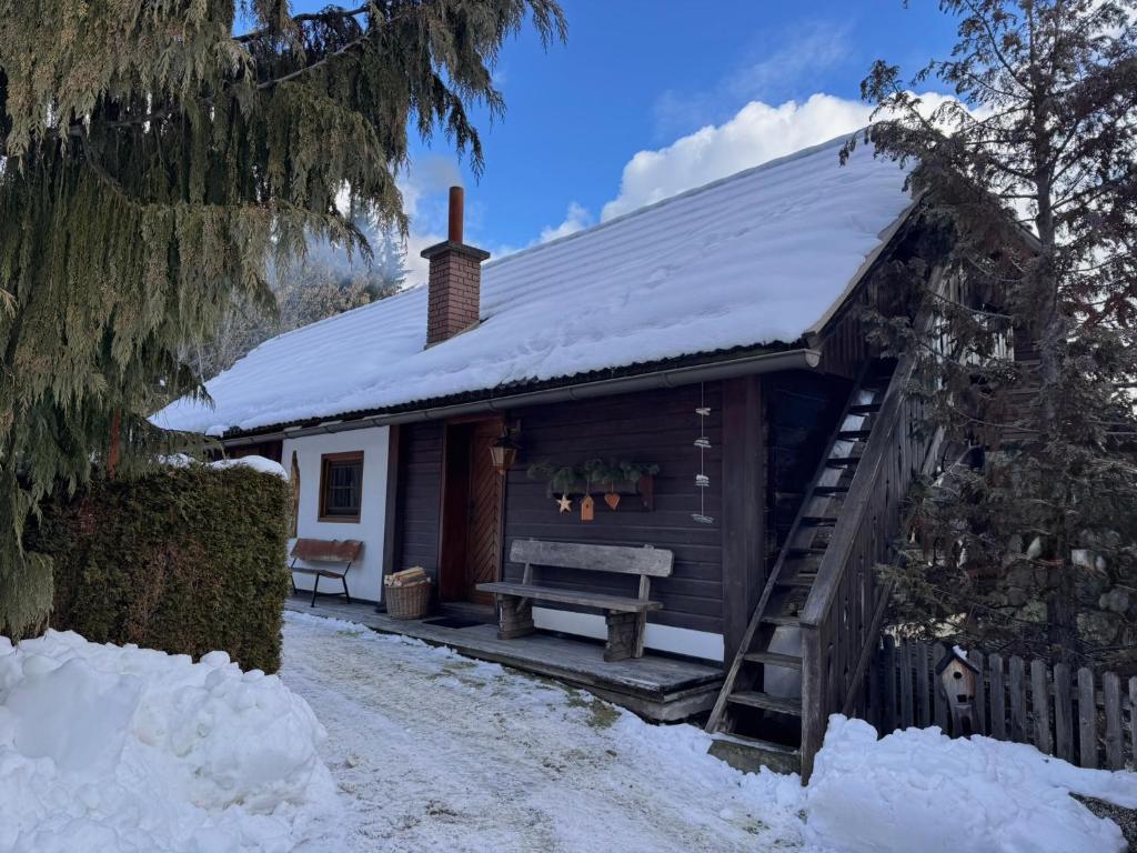 a cabin with a bench in the snow at Ferienhaus Niederbichler in Gnesau