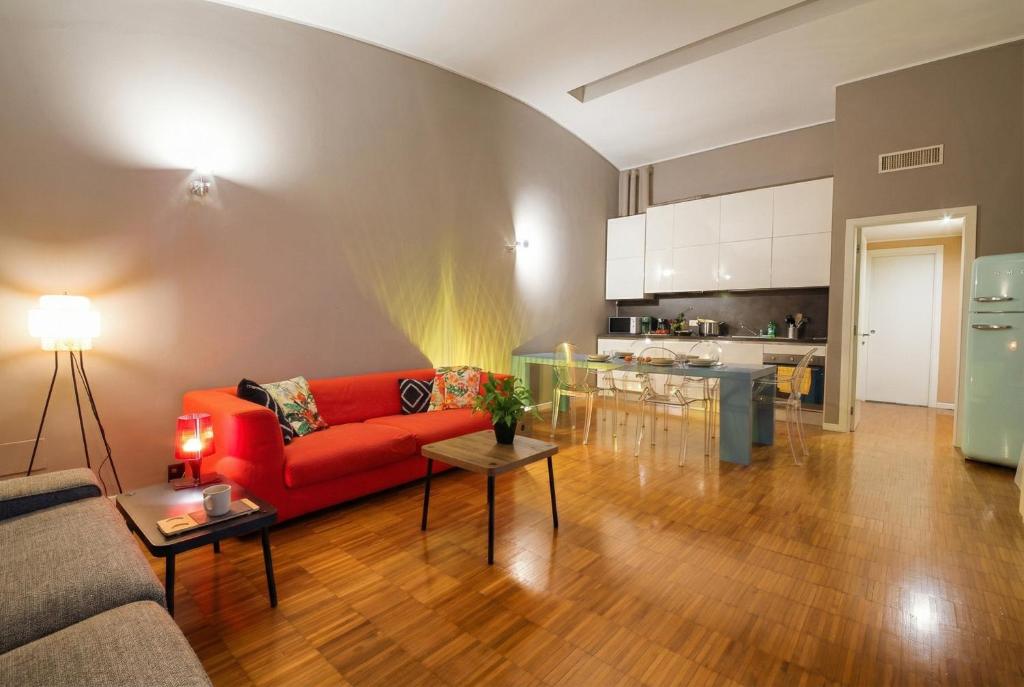 a living room with a red couch and a kitchen at Navigli Experience in Milan