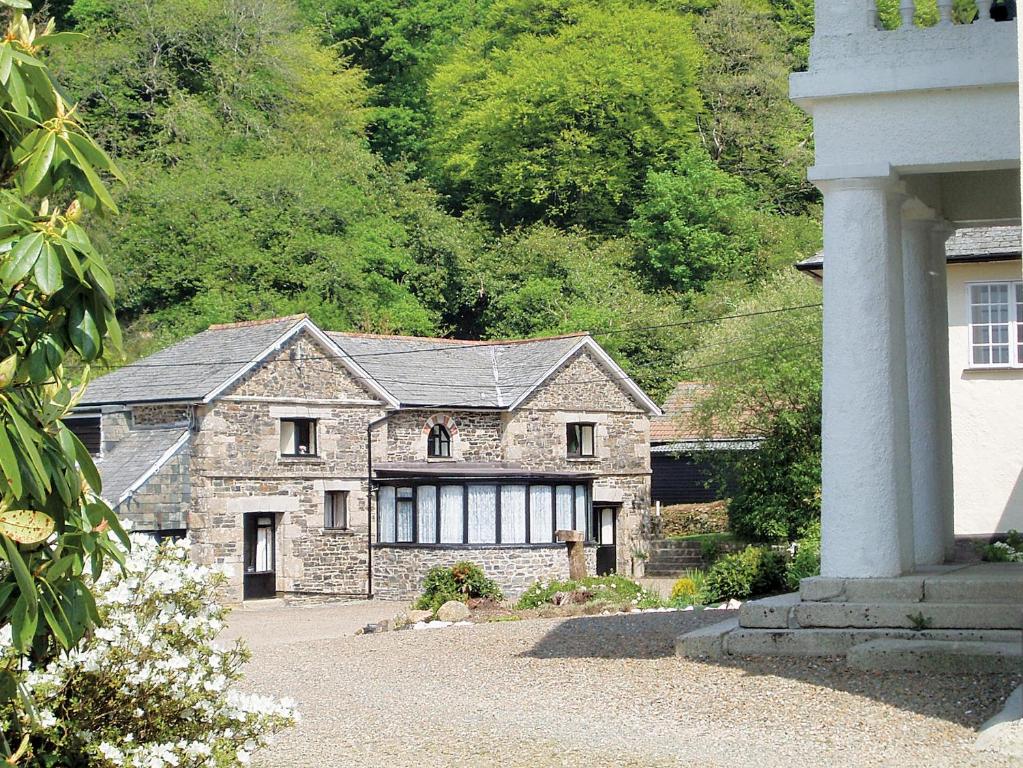 a large stone house in front of a mountain at Rosecraddoc Manor - Coachman's in Saint Cleer