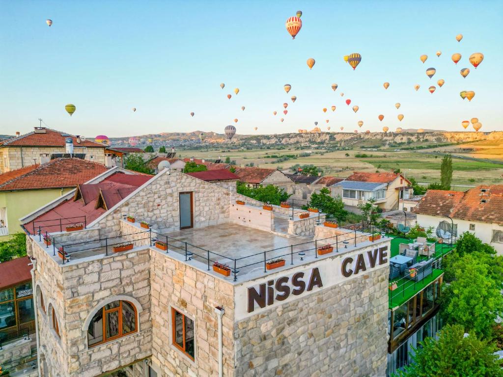 a group of hot air balloons flying over a city at Nissa Cave in Göreme