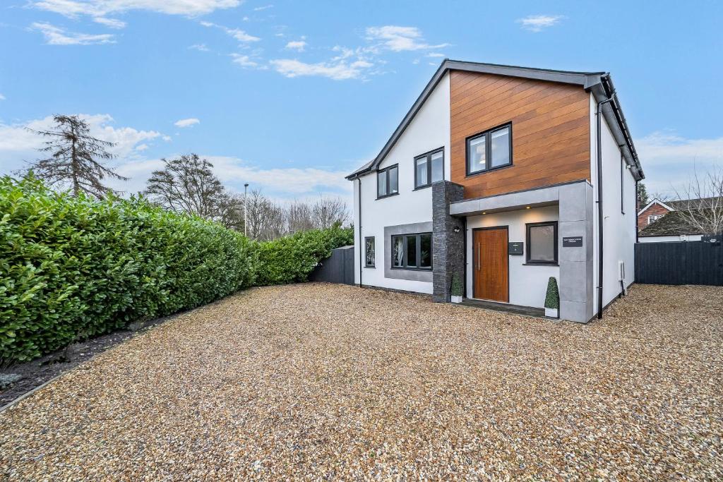 a house on a gravel driveway with a fence at Winterbourne House in Fleet