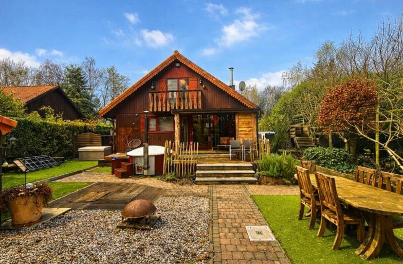 a small house with a table and chairs in a yard at Le Petit Chalet avec hottub. in Sint-Gillis-Waas