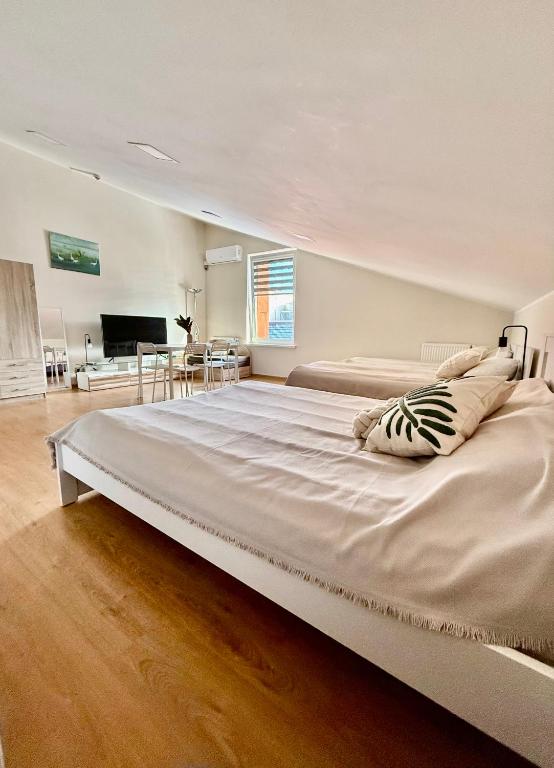 a large white bed in a bedroom with a living room at Perlos Apartamentai 12 in Birštonas