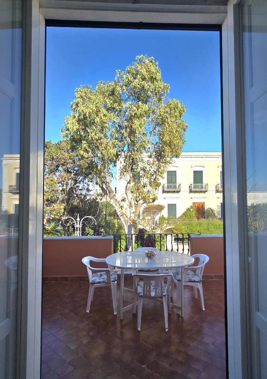 a white table and chairs on a patio with a tree at La Casetta Sul Corso in Ischia Town
