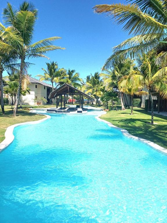 a pool of blue water next to a beach with palm trees at Casa meravigliosa vicino alla spiaggia con grande piscina e giardino in Beberibe