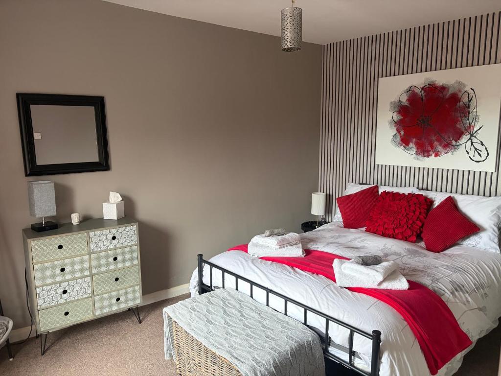 a bedroom with a bed with red pillows and a dresser at Roseus and Mimosa Cottages in Combe Martin