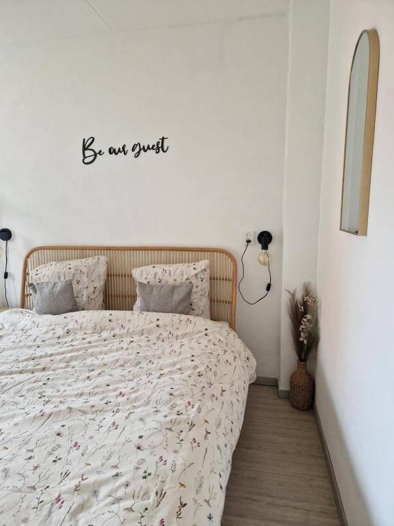 a bedroom with a bed with a be our guest sign on the wall at Appartement op topligging! in Cadzand