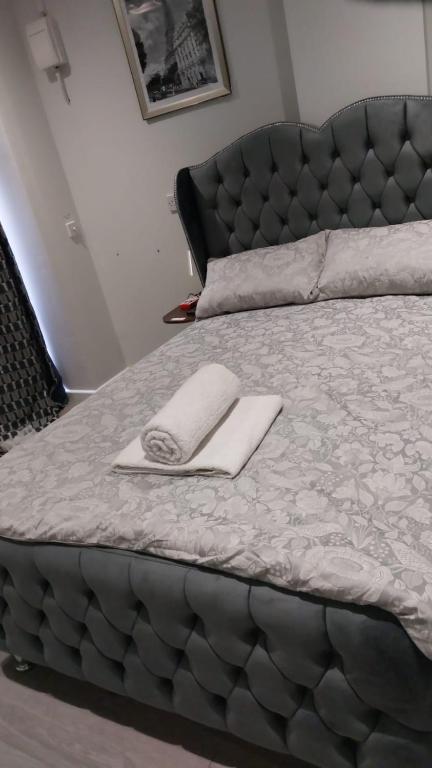 a bed with a black headboard and a white towel on it at Serene and Cosy Private Studio in Milton Keynes