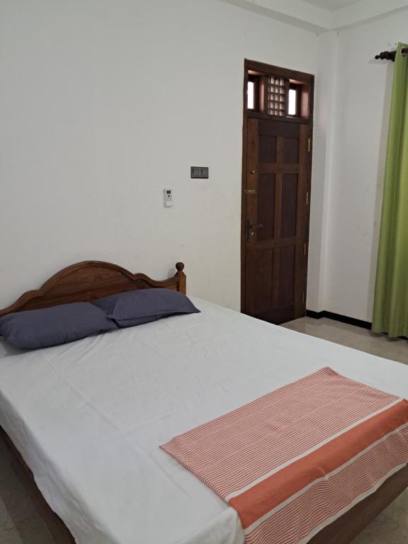 a bedroom with a bed with a wooden headboard and a door at Home mr in Matara