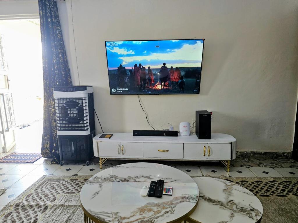 a living room with a table and a tv on the wall at Deripacs Homes in Lodwar