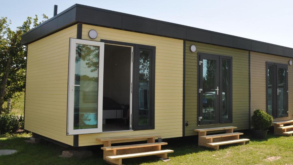 a green tiny house with benches in the grass at Surf Shack 1 - Zimmer nah am Meer, WLAN, Gemeinschaftsgarten, Surfschule, Naturstrand, Parkplatz, Radfahrweg, Promenade in 10 Minuten erreichbar, Stopover Puttgarden in Dahme