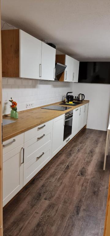 a kitchen with white cabinets and a wooden floor at Pension am Bach Nice Dreamis in Fuldatal