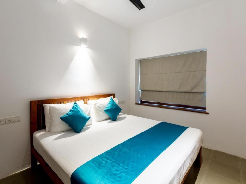a bedroom with a bed with blue pillows and a window at Serendipity in Colombo