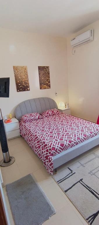 a bedroom with a bed with a red and white comforter at bel studio de luxe a thies Sénégal in Thiès