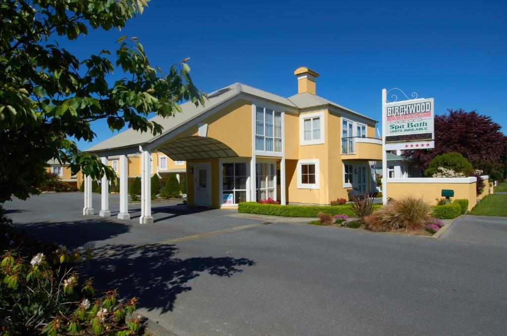 un gran edificio amarillo con un cartel delante en Birchwood Manor, en Invercargill