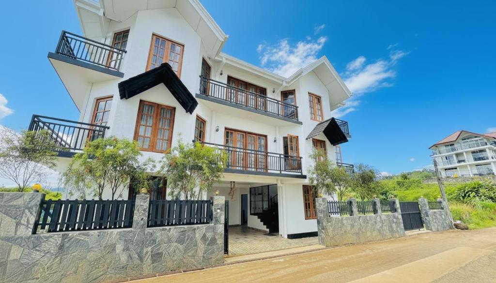 a white house with balconies on it at Ru Hotel & Villa in Nuwara Eliya
