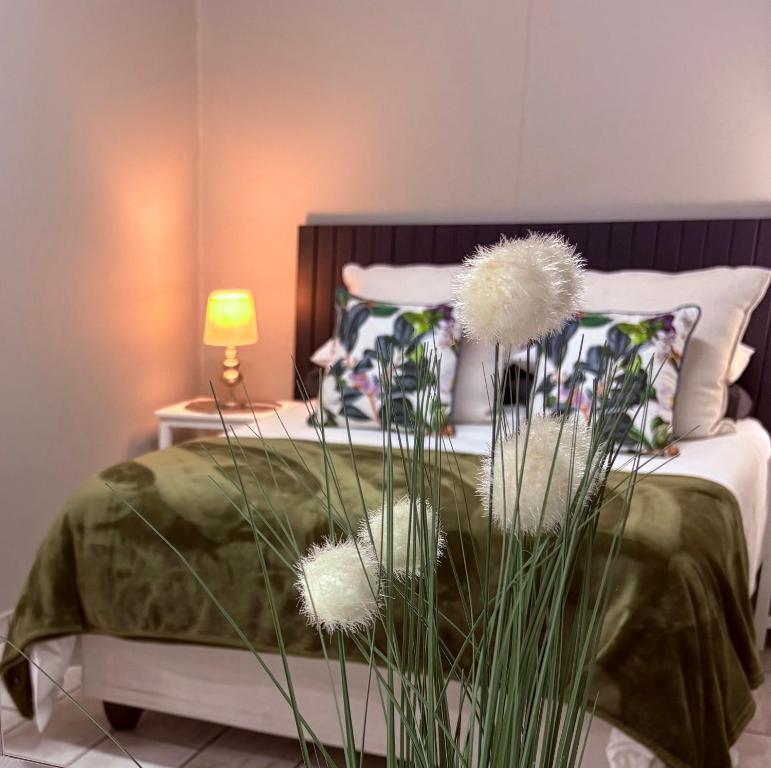 a bedroom with a bed with green sheets and flowers at Happy Daze Spacious 45m2 Self Catering Apartment in Swellendam