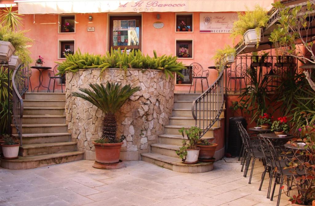 a building with stairs and plants in front of it at Hotel Il Barocco in Ragusa