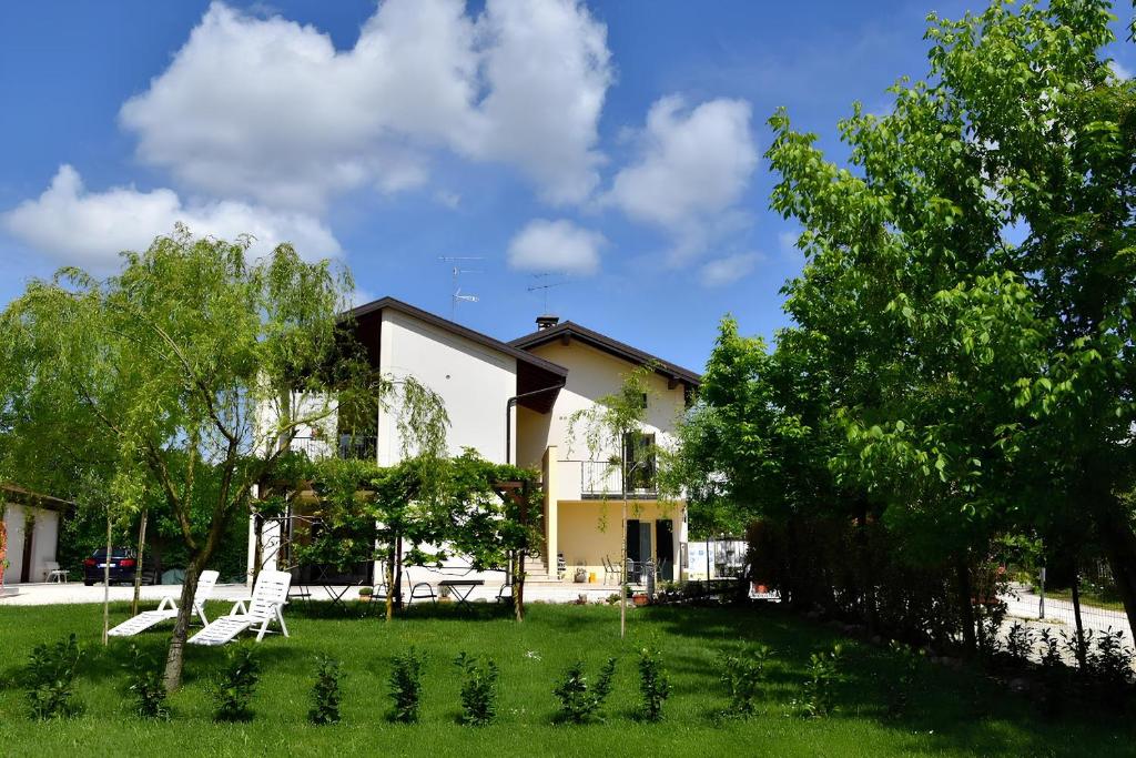 a house with two white chairs in the yard at B&B Il Grande Salice Bike Friends in Ponti Sul Mincio