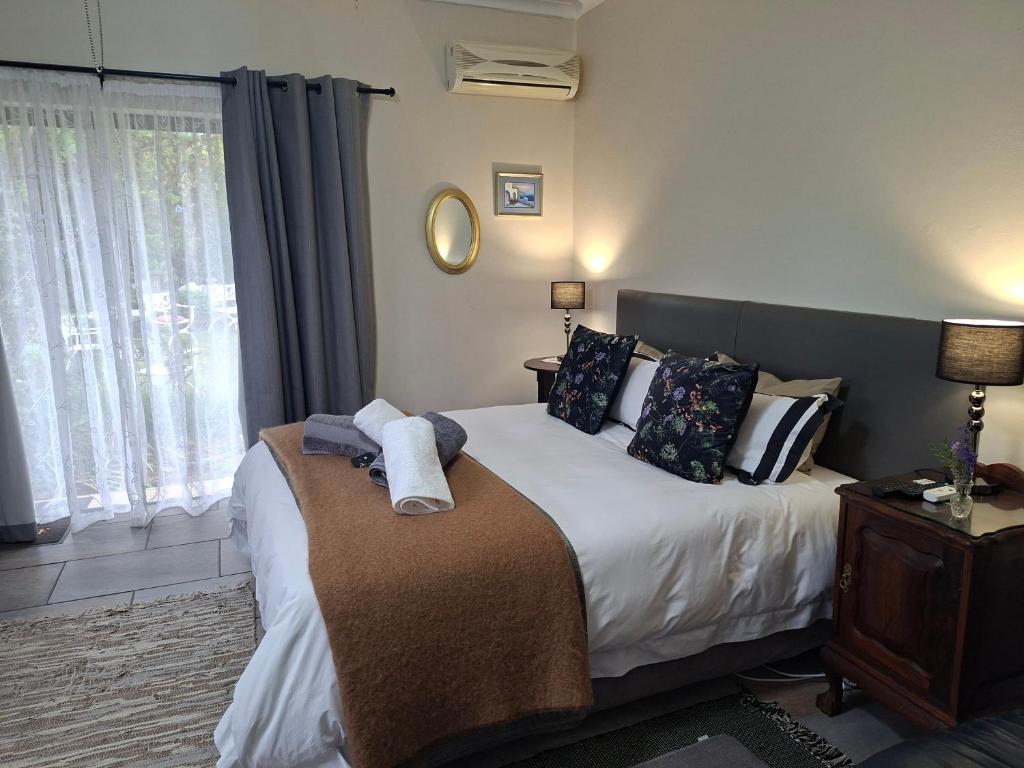 a bedroom with a bed with towels on it at 1-On-Scott Garden Suites in Somerset East