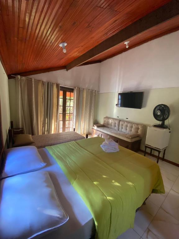 a bedroom with a green bed and a desk at Maria Candida Hospedaria in Areias