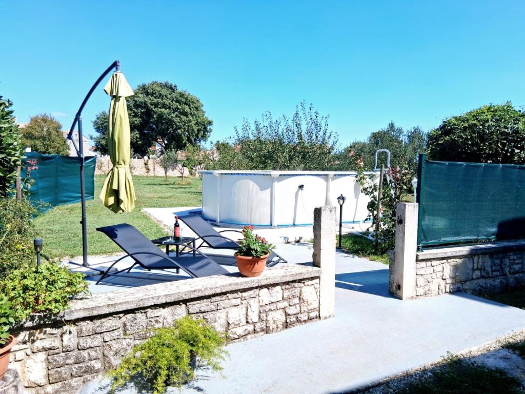 a patio with two chairs and an umbrella at Apartment Glavani with Pool in Barban