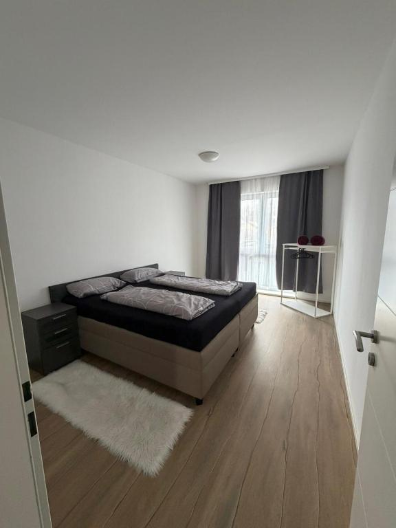 a white bedroom with a bed and a window at Ruhige Wohnung in Linz