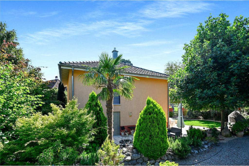 a house with a palm tree in a garden at Alpine View Thierachern in Thierachern