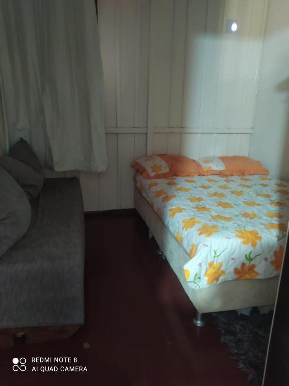 a bedroom with a bed and a couch in it at Casa da vó in Jaguaruna
