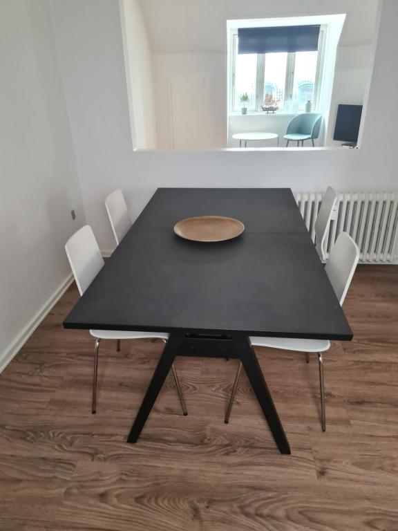 ein schwarzer Esstisch mit weißen Stühlen in der Unterkunft Suite 3 in Frederikshavn