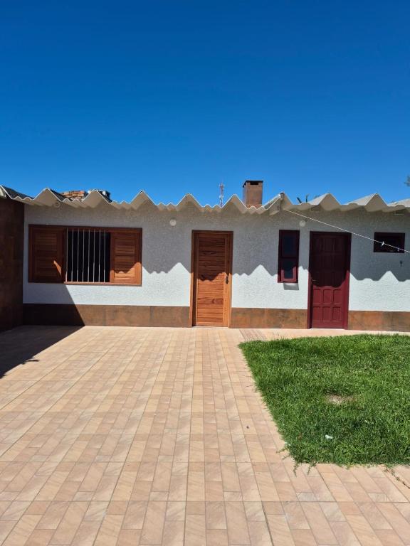 a building with two doors and a grass yard at El Tata in Arroio do Silva