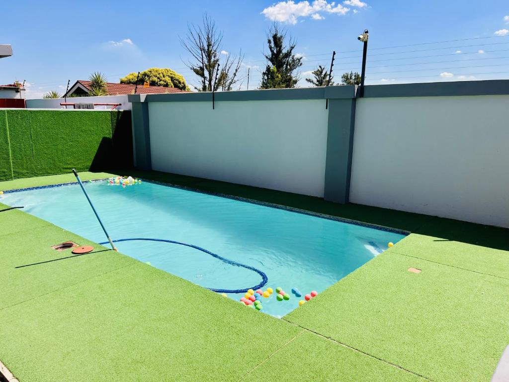 a small swimming pool with a white wall at Zindiza Guesthouse in eMalahleni