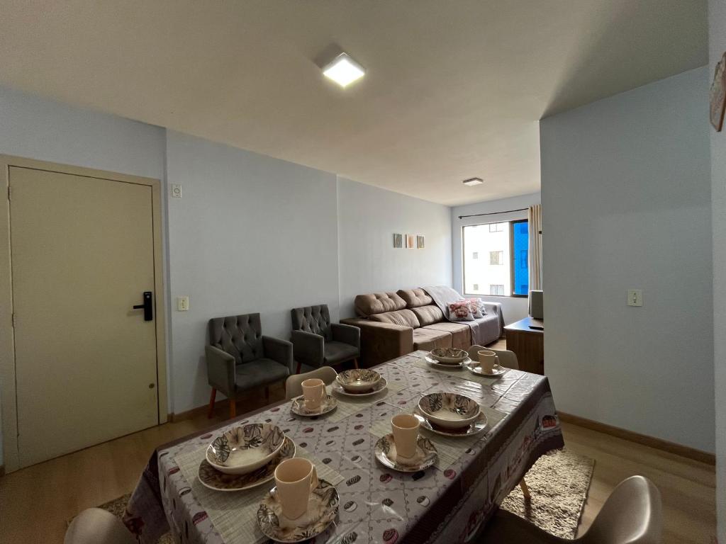a living room with a table with dishes on it at Apartamento Mobiliado com internet e ar condicionado no centro in Cascavel
