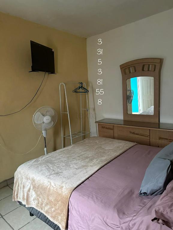 a bedroom with a bed and a tv on the wall at Cuarto a 4min del aeropuerto in Guadalajara