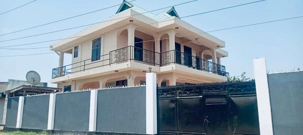 a house with a balcony on top of a fence at Agape hostel in Bagamoyo