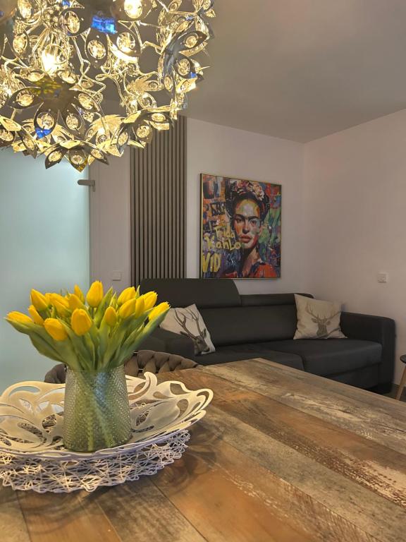 a dining room table with a vase of yellow flowers at FERIENWOHNUNG TRUNK, kühl, direkt an den Weinbergen, Parkplatz, Terrasse mit Grill und Lounge in Roschbach