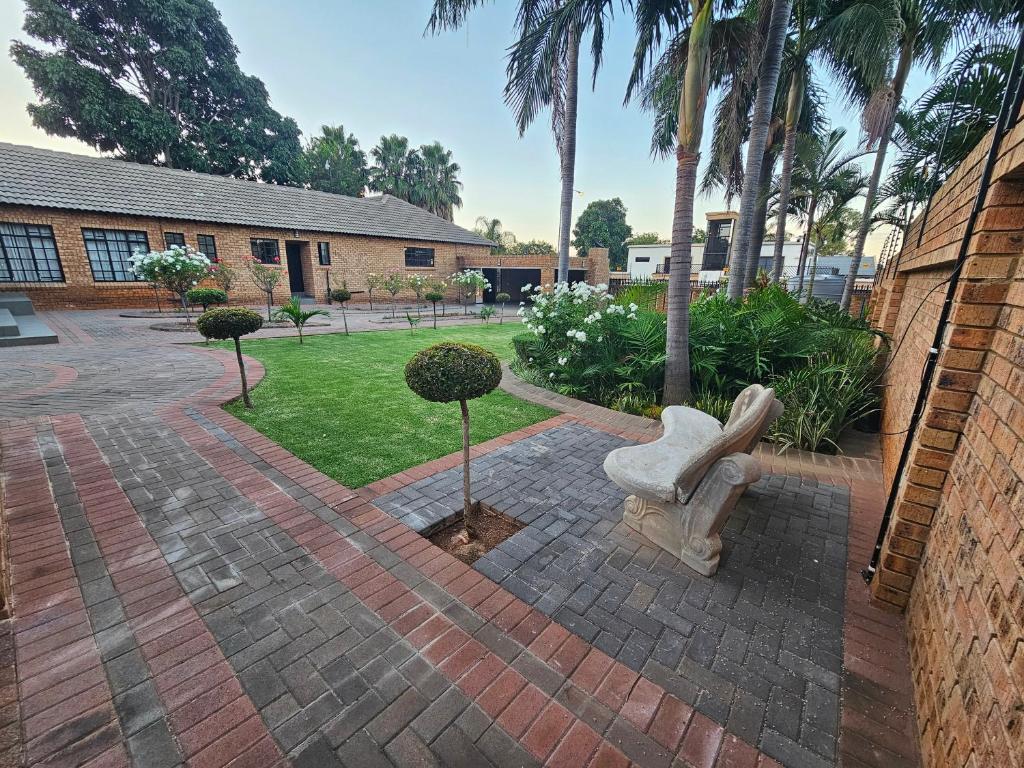 a park with a bench and palm trees and a building at A Pearl Place in Pretoria