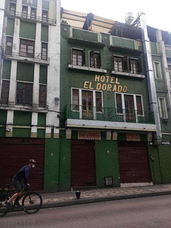 a man riding a bike in front of a building at Hotel el Dorado La Candelaria in Bogotá