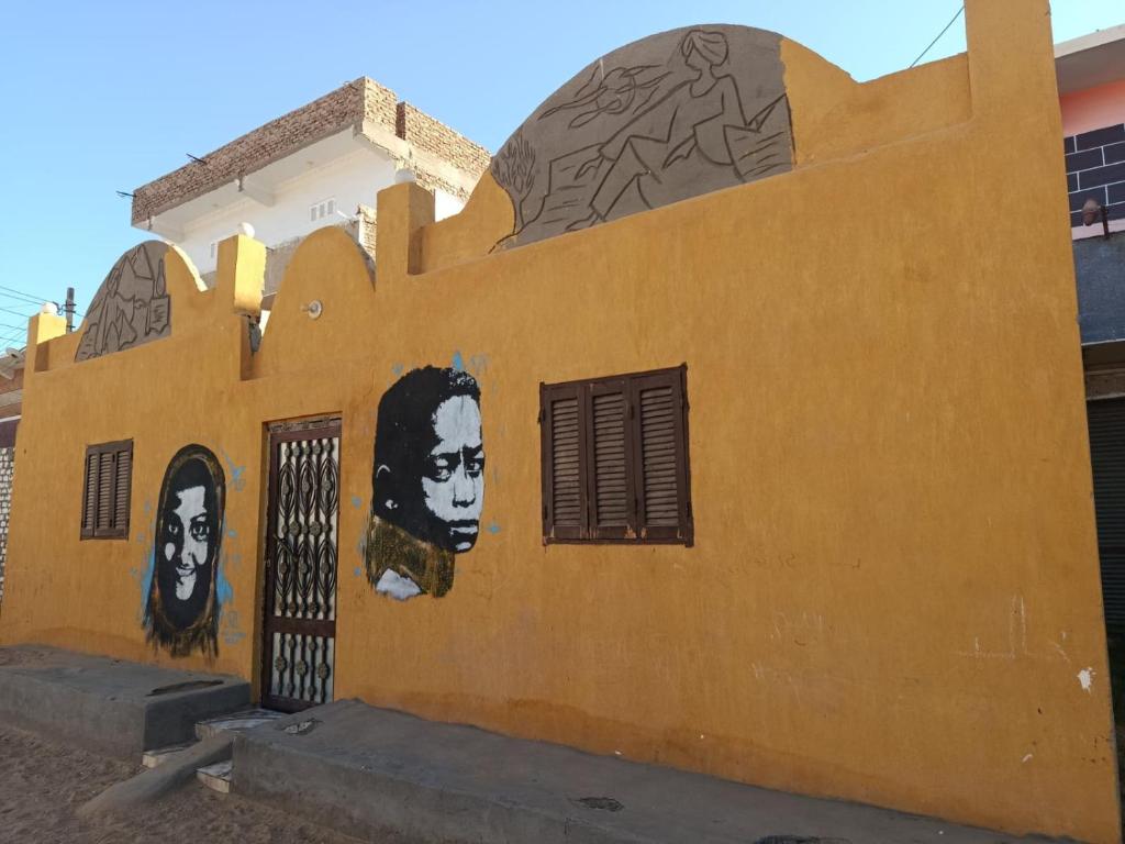 a yellow wall with two faces painted on it at Rooma ka Guest House in Aswan
