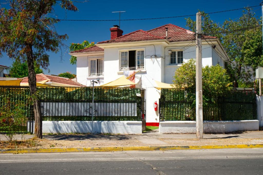 a white house with a gate in front of it at Hostal Estadio Nacional in Santiago