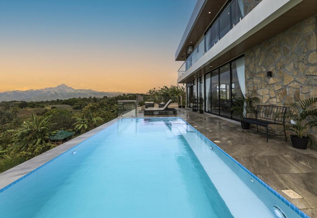 a swimming pool in front of a house with a view at Villa 360 in Calaca