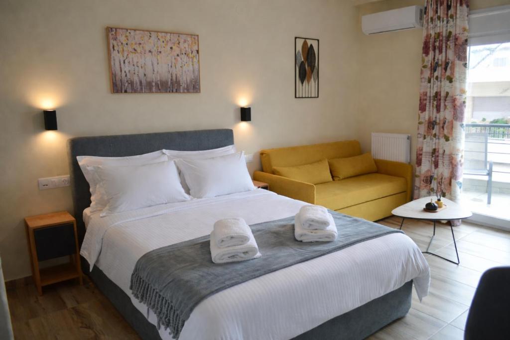 a bedroom with a large bed and a yellow couch at GoCity apartments in Volos