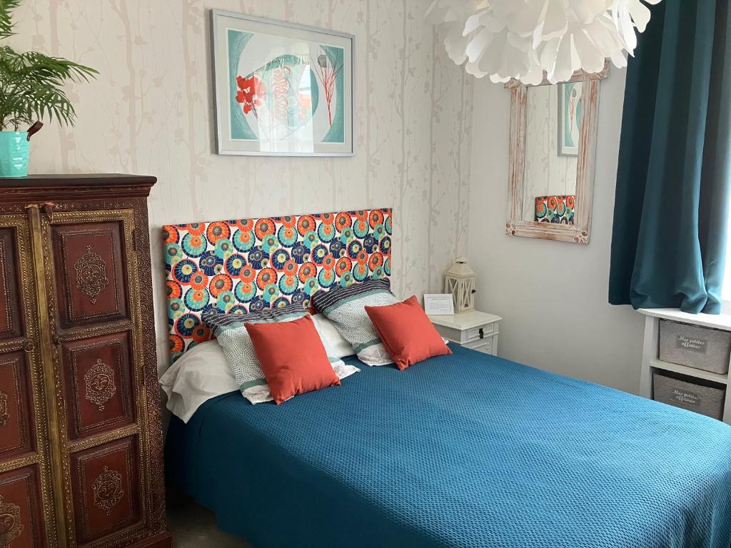 a bedroom with a blue bed with red pillows at Chambres dans maison atypique in Ille-sur-Têt