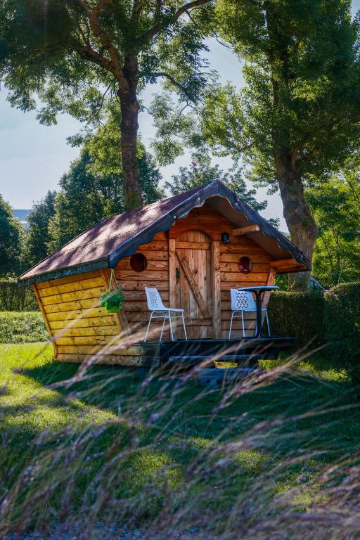a log cabin with two chairs in front of it at Camping l'Estela sur le GR70 in Le Monastier sur Gazeille