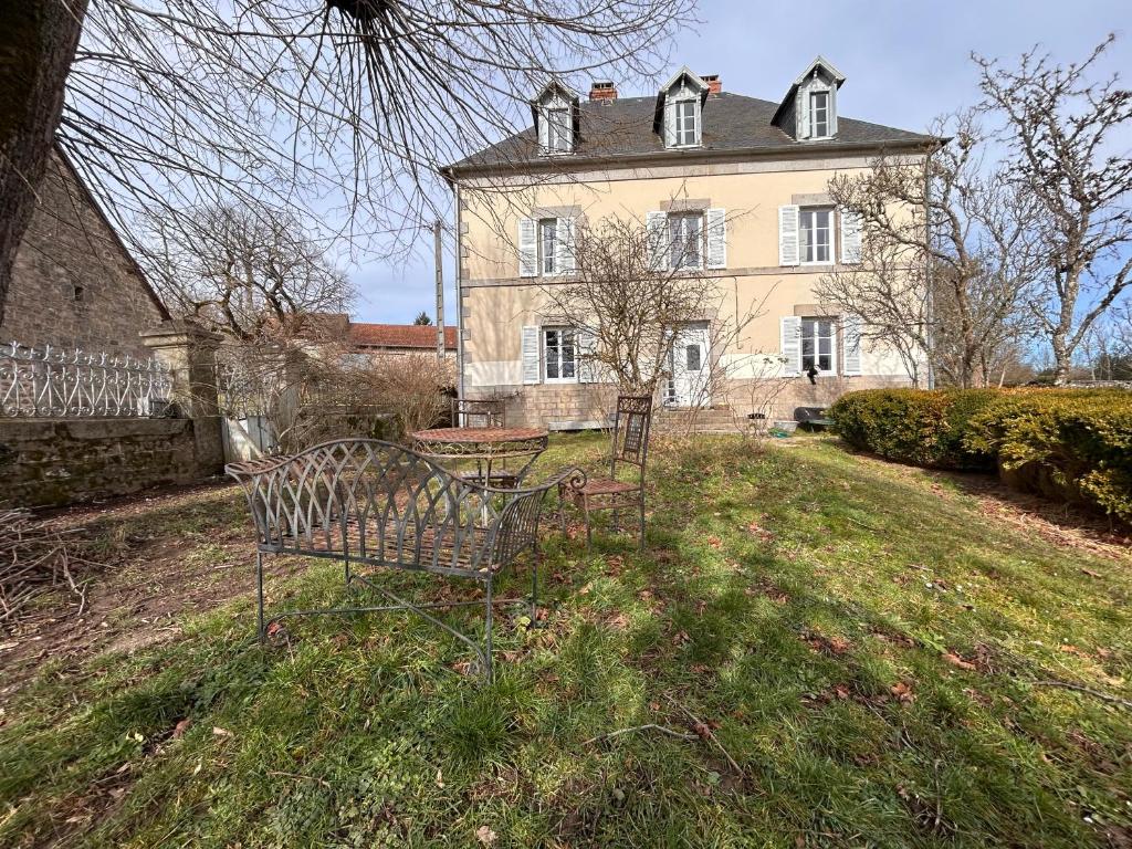a bench in front of a large house at Grande maison Albuconis in Saint-Oradoux-près-Crocq