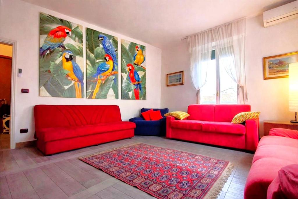 a living room with two red couches and a painting of birds at Cappuccini Florence your easy stay close to the center in Florence